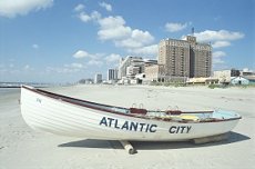 small boat on beach with atlantic city in background.